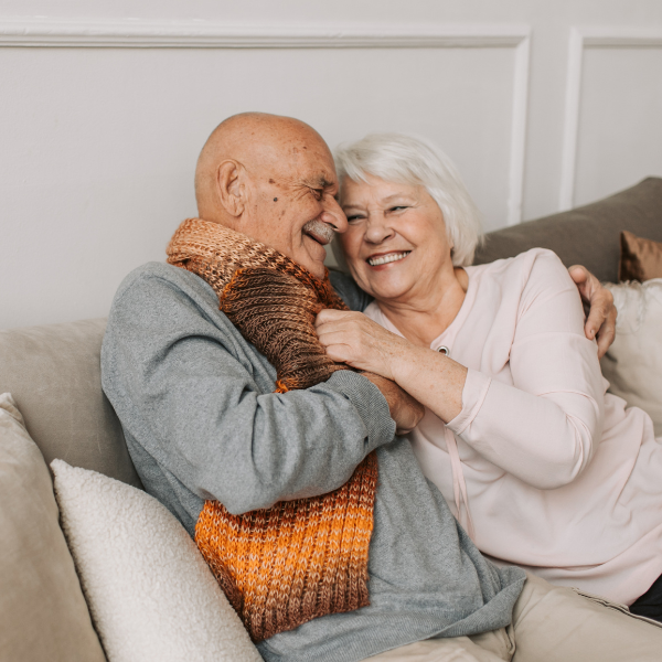 An older couple embracing and laughing at home